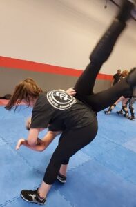 A picture of a female Warriors Krav Maga instructor throwing someone with a hip throw.